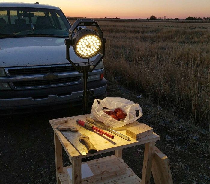 Portable LED work light at a tidy outdoor campsite at night — AI-generated illustrative scene
